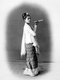 The cheroot that the young woman holds is a typical attribute in studio portraits of Burmese women, whose custom of smoking large cigars was noted with some astonishment by European visitors, who also commented on their relative freedom, beauty and confidence.<br/><br/>

She wears a striped silk <i>hta-mein</i> (wrap-around skirt) and a close-fitting jacket of fine muslin or cotton known as an <i>ein-gyi</i>. Her hair is adorned with a floral headband and she wears necklaces and earrings.<br/><br/>

During the Konbaung Dynasty (1752-1885), rich jewellery, fine fabrics such as silk and garments such as her jacket were reserved for court officials and their wives by law. After the fall of the Burmese monarchy in 1885 they were worn by the wealthy.<br/><br/>

This photograph is from an album recording aspects of Lord Elgin's Burma tour of November to December 1898. Victor Alexander Bruce (1849-1917), 9th Earl of Elgin and 13th Earl of Kincardine, served as Viceroy of India between 1894 and 1899.